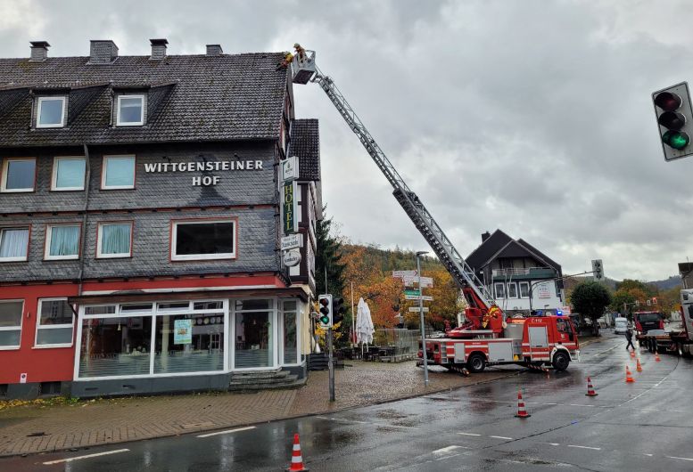 Feuerwehrauto hat die Drehleiter ausgefahren. Feuerwehrmann sichert Dachpfannen.