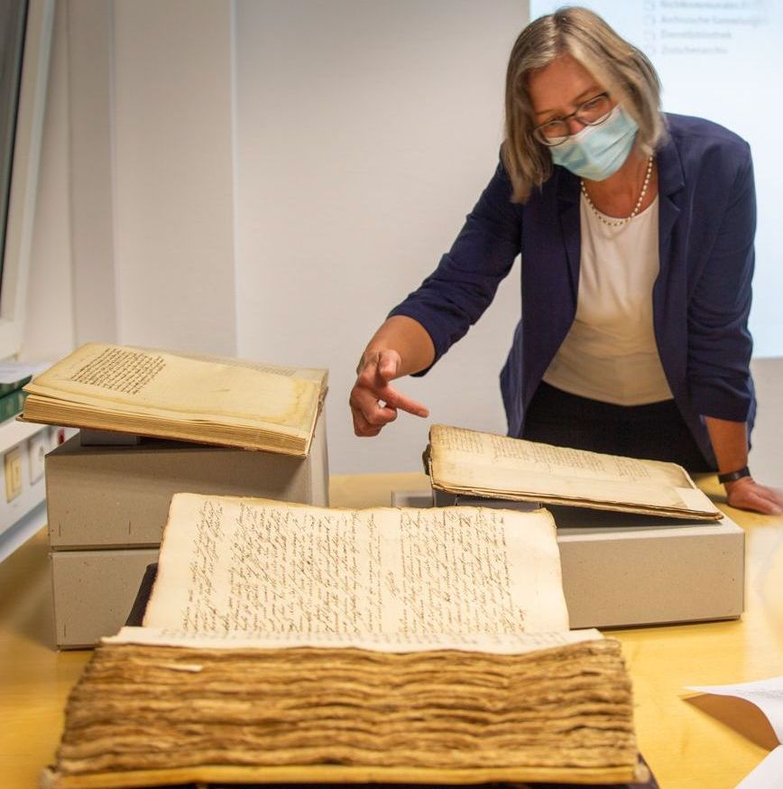 Frau um die 50 vor alten Büchern und Dokumenten