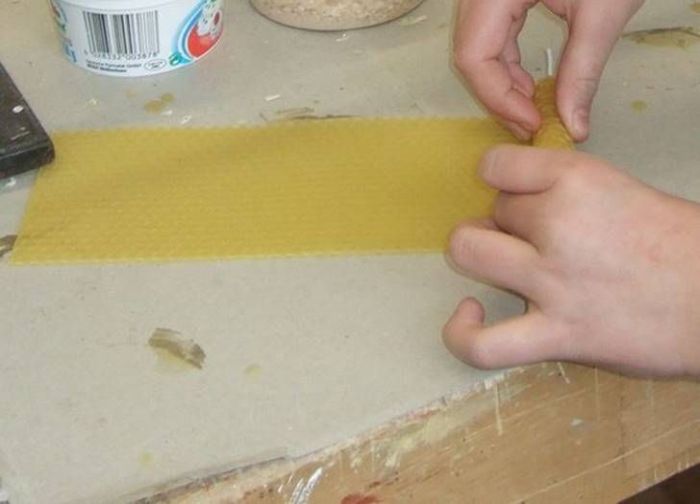 Kinderhände rollen einen Bienenwachs-Kerze