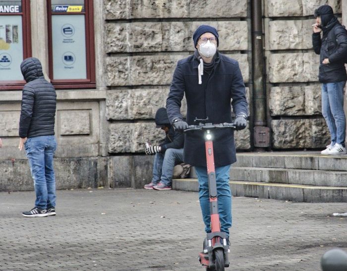 Mann auf eScooter - dahinter Passanten