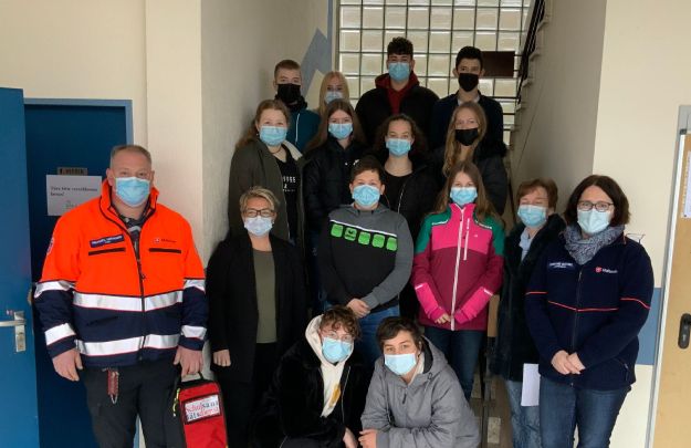 Maskierte Schulsanitäter mit Lehrpersonal beim Gruppenfoto