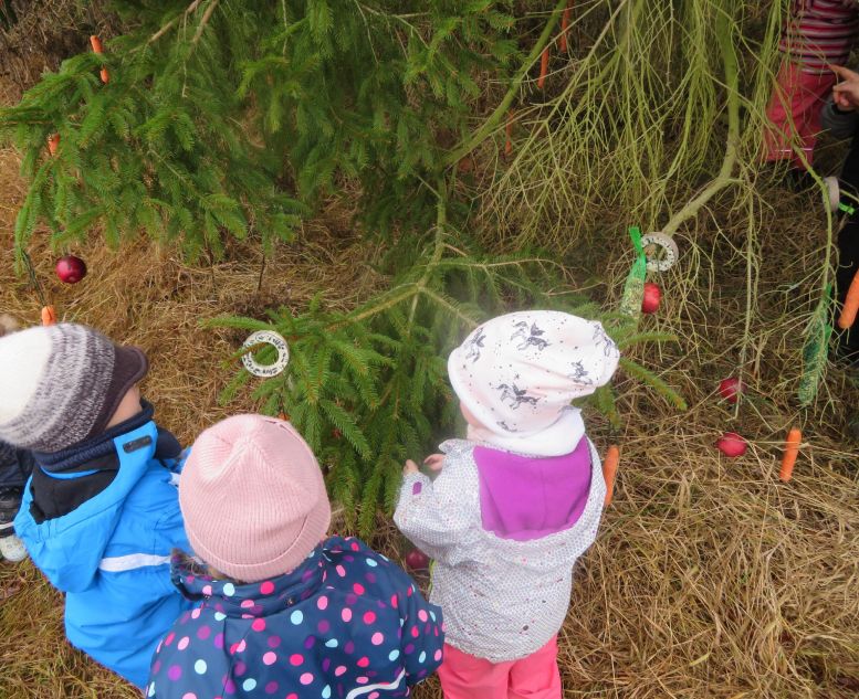 3 Kinder von hinten schmücken einen Waldbaum