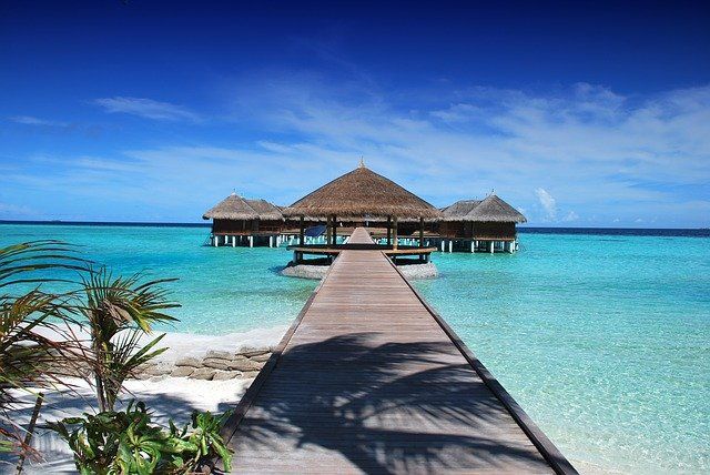 Malediven. Strand, Steg, Hütten. Blaues Meer, blauer Himmel.