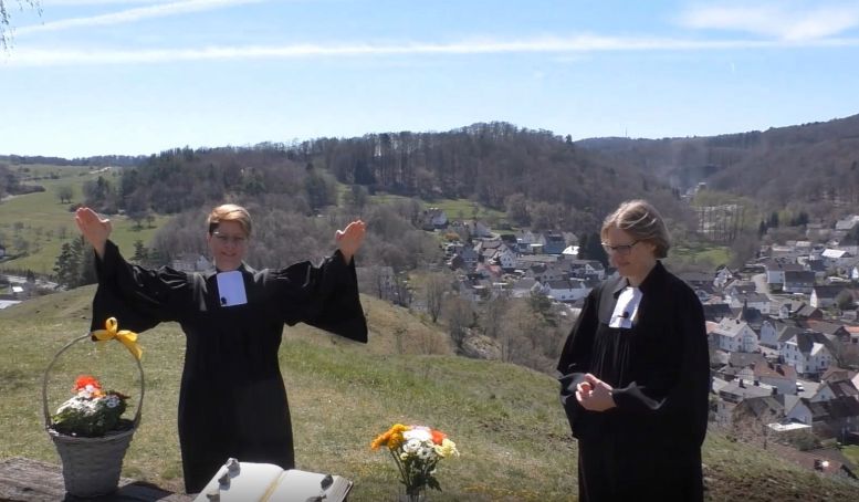 2 Pfarrerinnen auf einer Wiese vor dem Altar