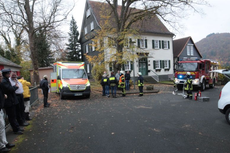 Krisenhelfer und andere stehen vor einem Haus herum, dazu Rettungswagen und Feuerwehrfahrzeug