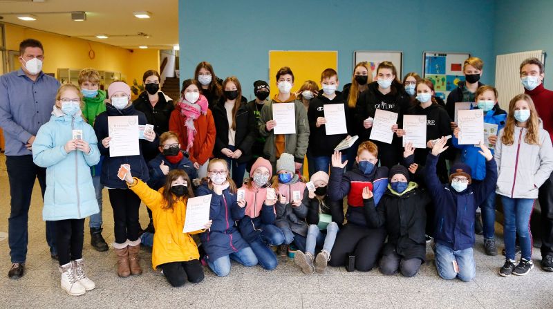 Maskierte Kinder und 2 Lehrer mit Urkunden