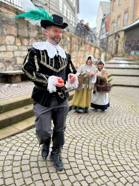 3 Schauspieler auf gepflastertem Platz in alten Kostümen
