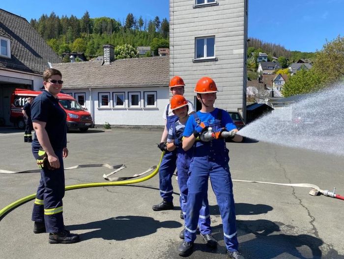 Feuerwehr-Nachwuchs arbeitet mit dem Strahlrohr. Prüfer schaut zu.