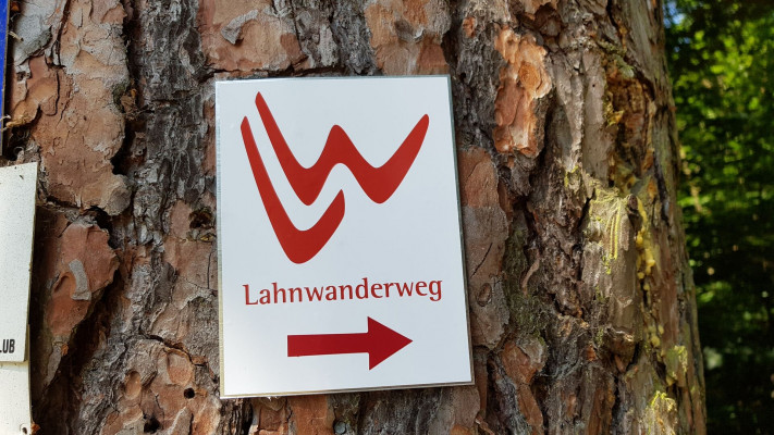 Schuld an einem Baum mit Logo des LahntalWanderwegs