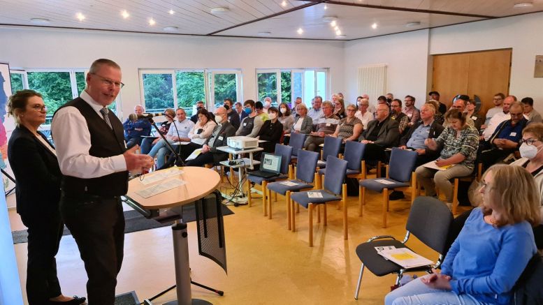 Haufen Leute in einem Raum sitzend. Referent steht