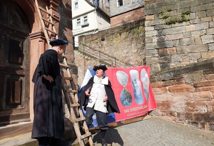 2 historisch Gewandete vor alter Kirche